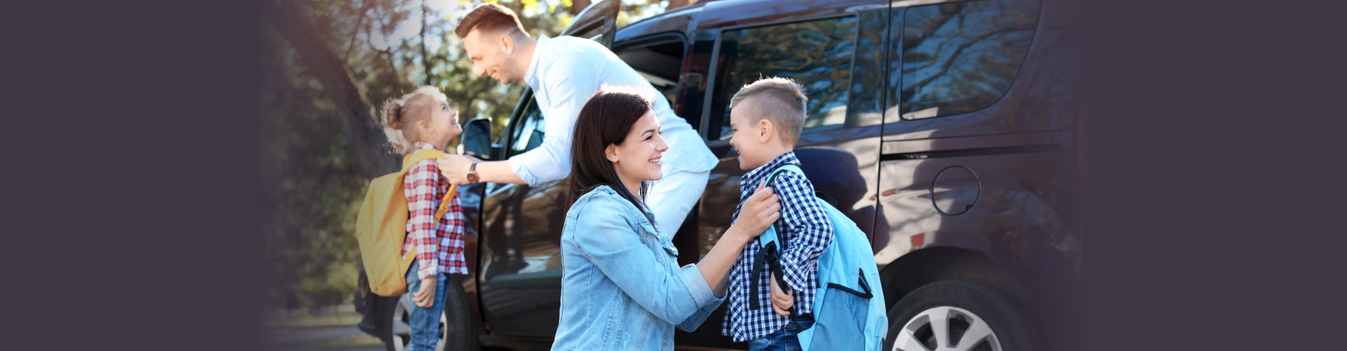 Young parents saying goodbye to their little children near school