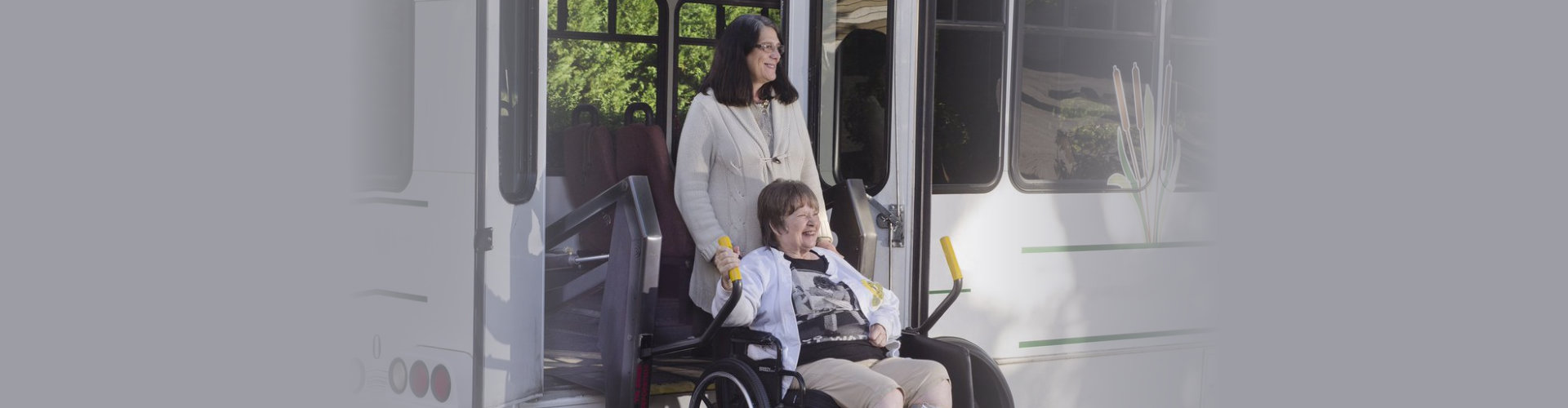 A woman in a wheelchair is helped off a van using a chair lift.